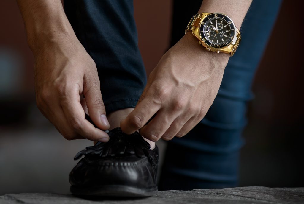 Homme qui fait ses lacets avec une montre de luxe au poignet